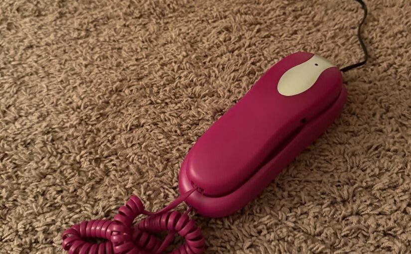 Purple push-button phone connected to a cord
